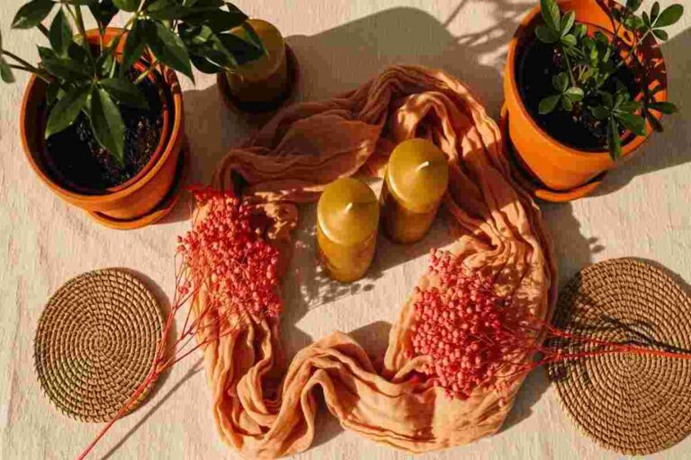 Candizi aesthetic flatlay with warm terracotta pots, coral dried flowers, golden candles, and natural woven placemats.